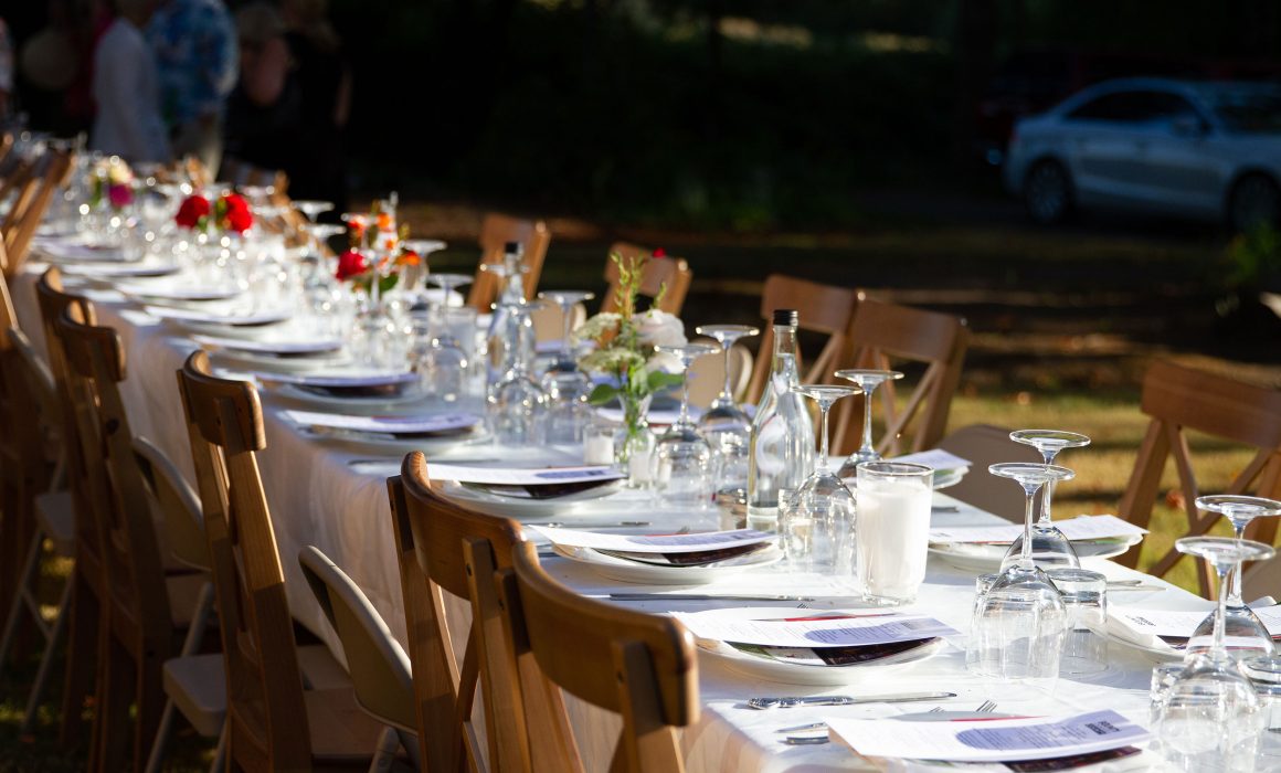 Table set outdoors farm style with glasses and wooden chairs