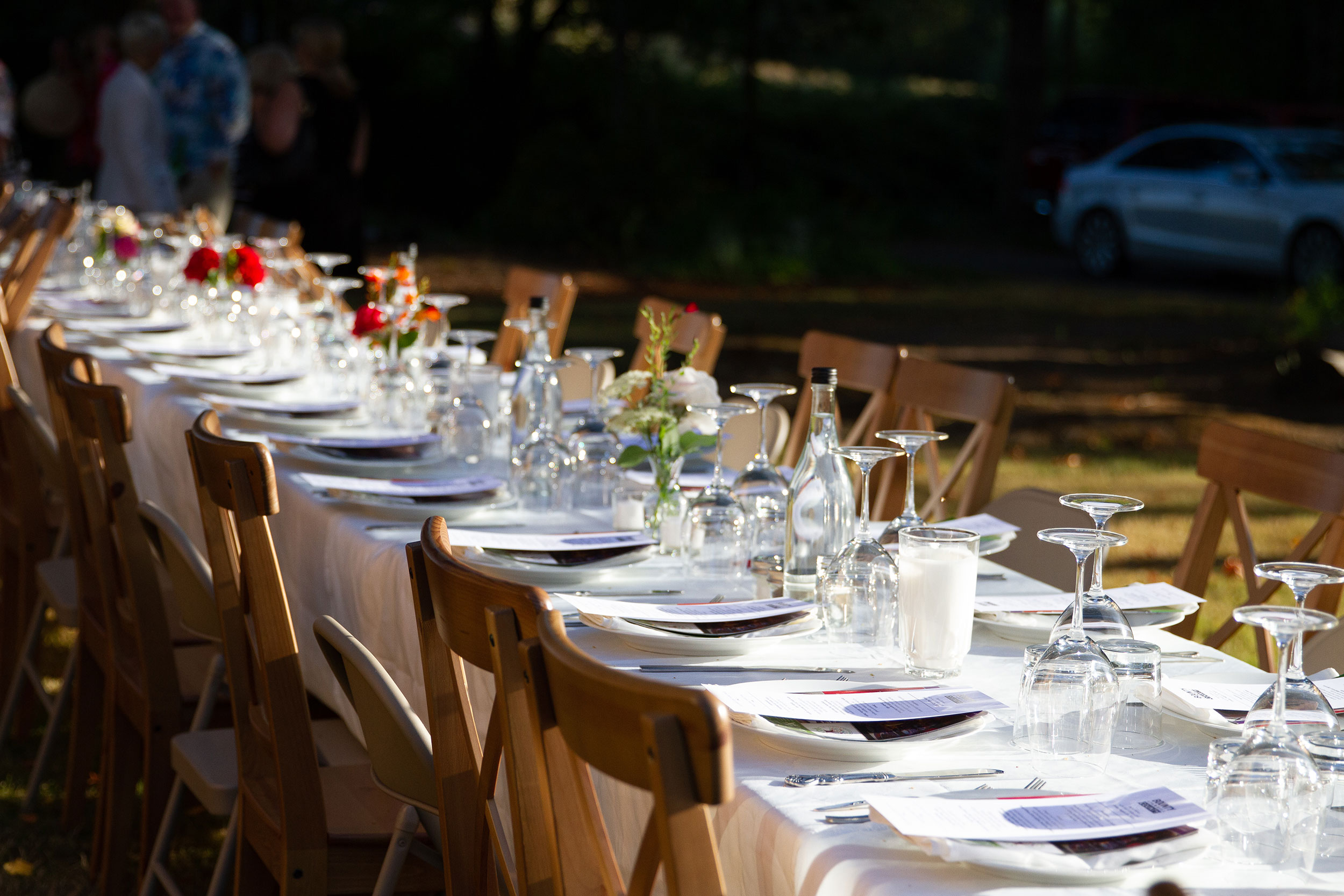 Table set outdoors farm style with glasses and wooden chairs