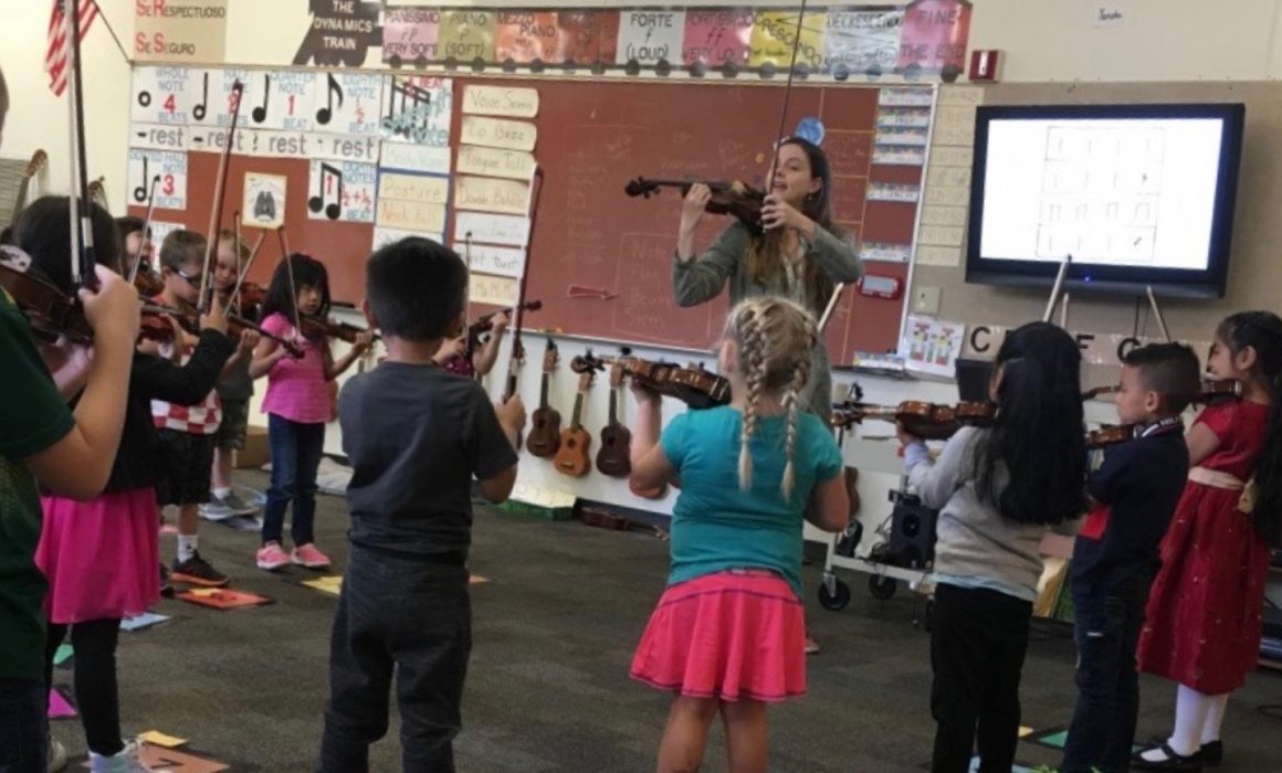 Instructor and students practicing their violins