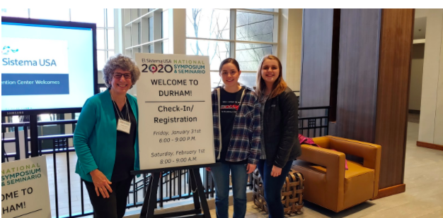 Three women next to a registration sign