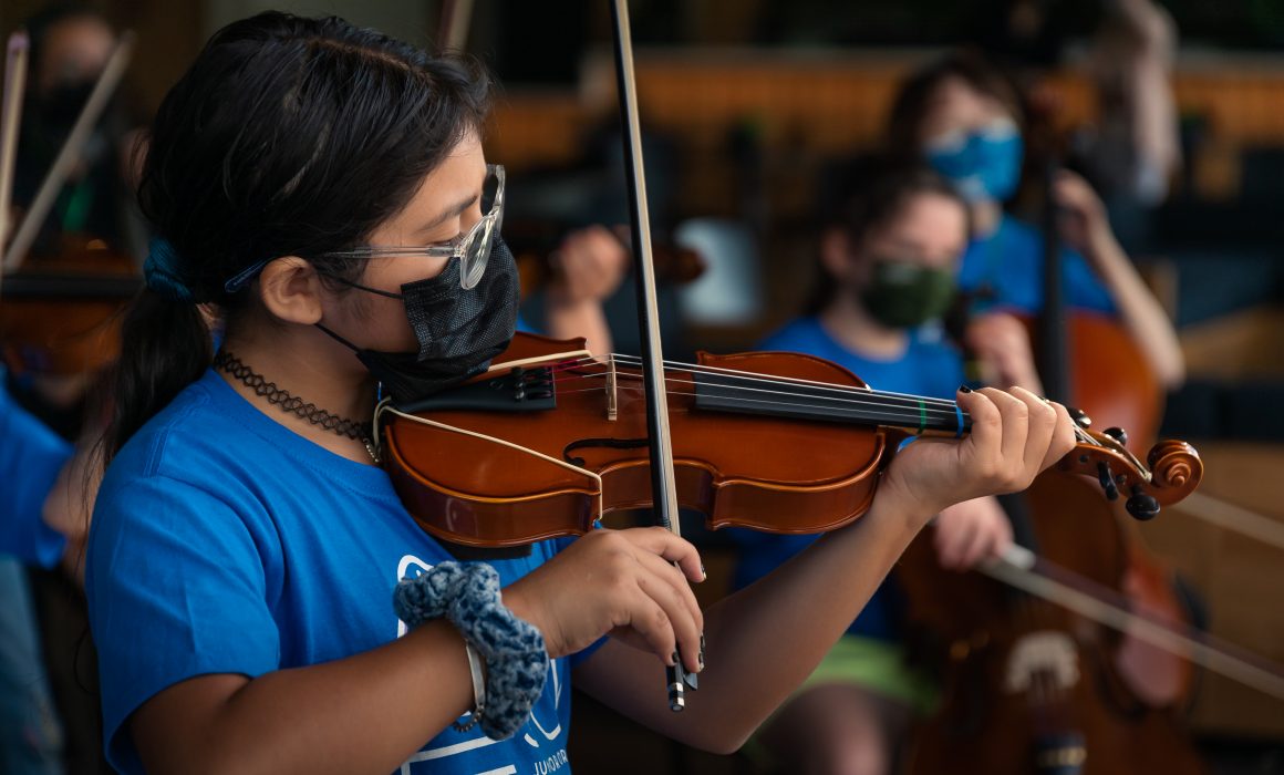 Children wearing masks and playing stringed instruments