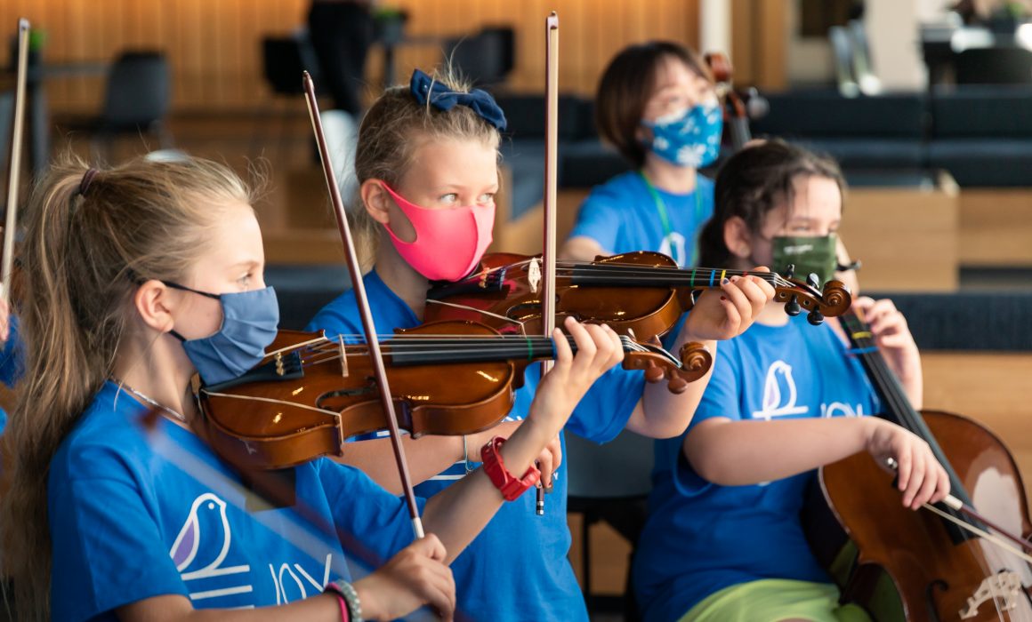 Children wearing masks and playing stringed instruments